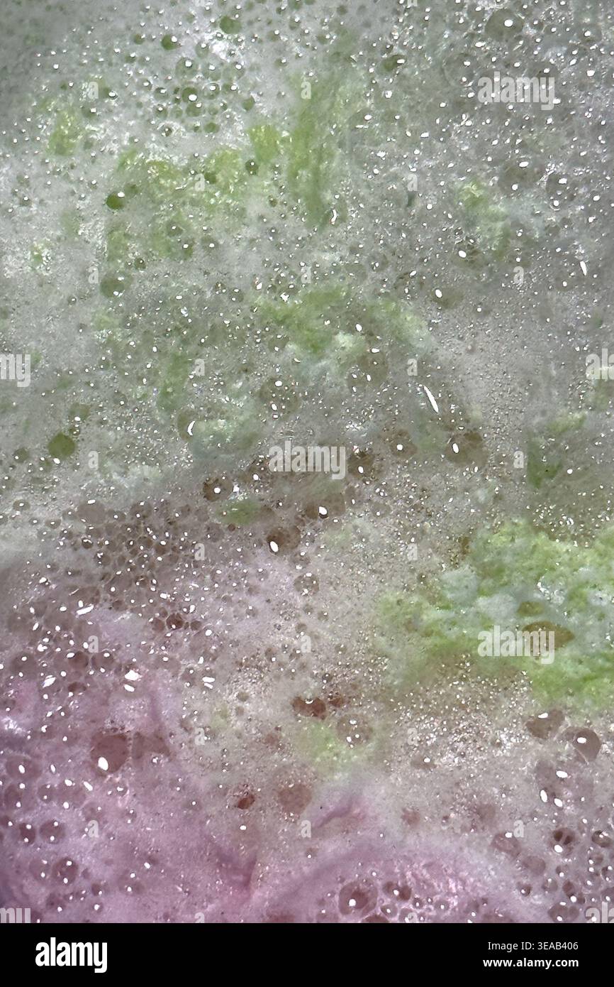 Colorful foam and bubbles produced by bath bombs in water, creates an organic, textured background element resembling a nebula scene from outer space. Stock Photo