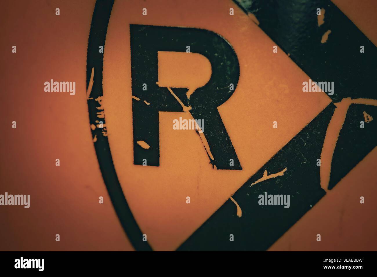 Macro closeup of radioactive hazard symbol with letter R on weathered ...