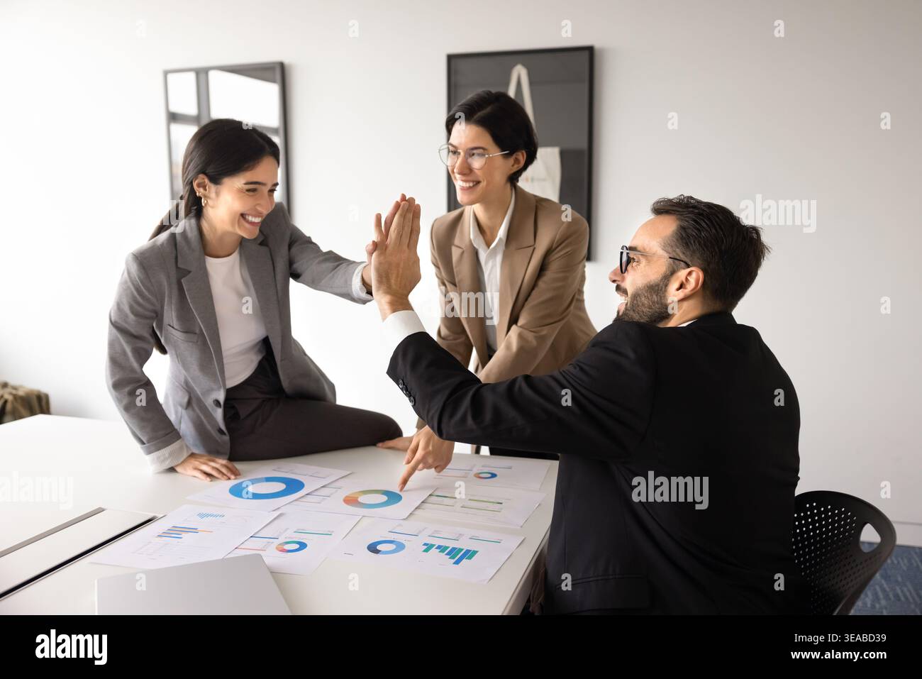 Diverse team celebrates project success with high five in office Stock Photo