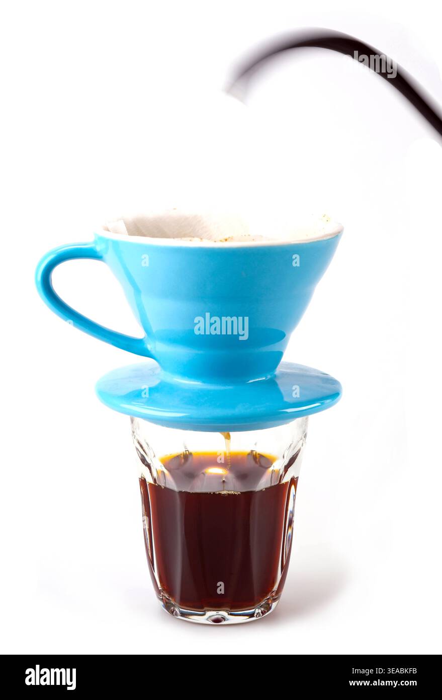 Professional manual drip coffee brewing with blue ceramic V60 dripper. Pouring hot water over coffee on white background. Stock Photo