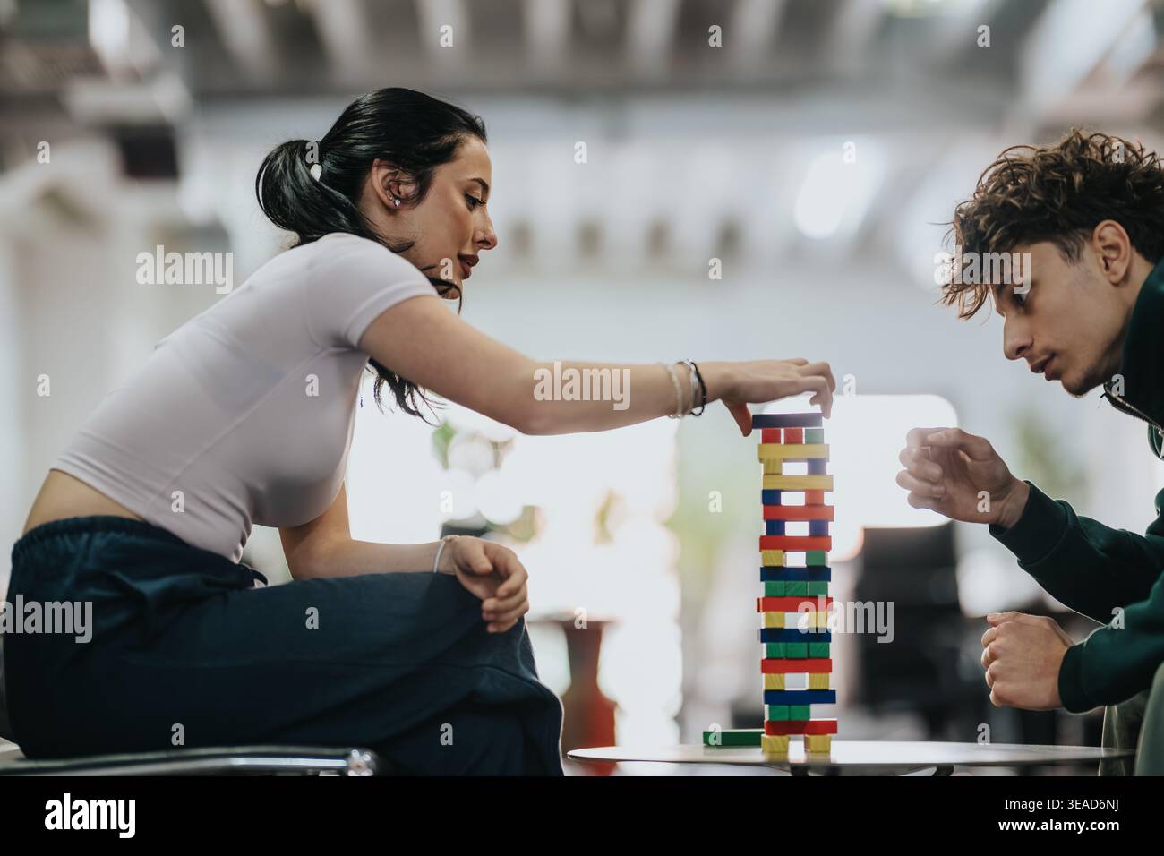 Two students concentrating while playing a block stacking game in a casual lounge Stock Photo
