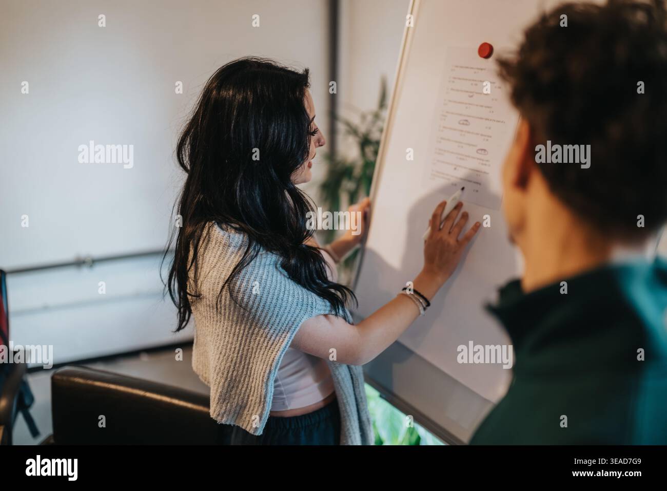 Two students collaborating at a whiteboard during a study session in a modern classroom Stock Photo