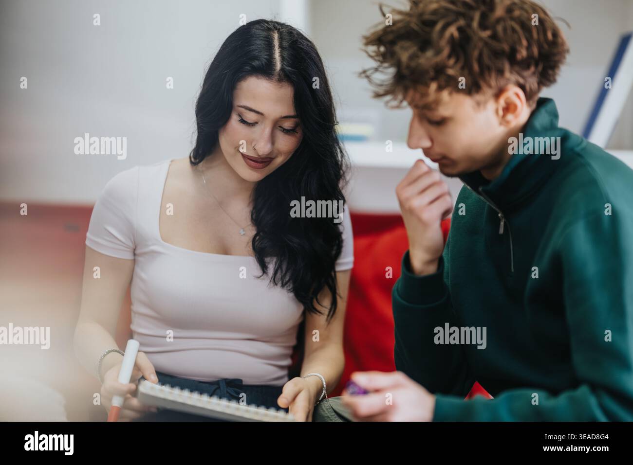 Two students studying together at home, collaborating on notes and learning in a casual setting Stock Photo