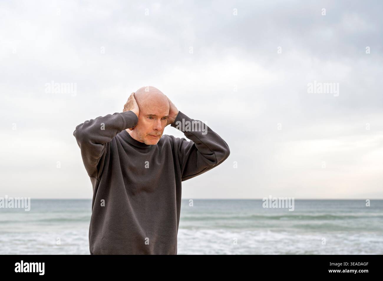 mature man standing with hands on head Stock Photo