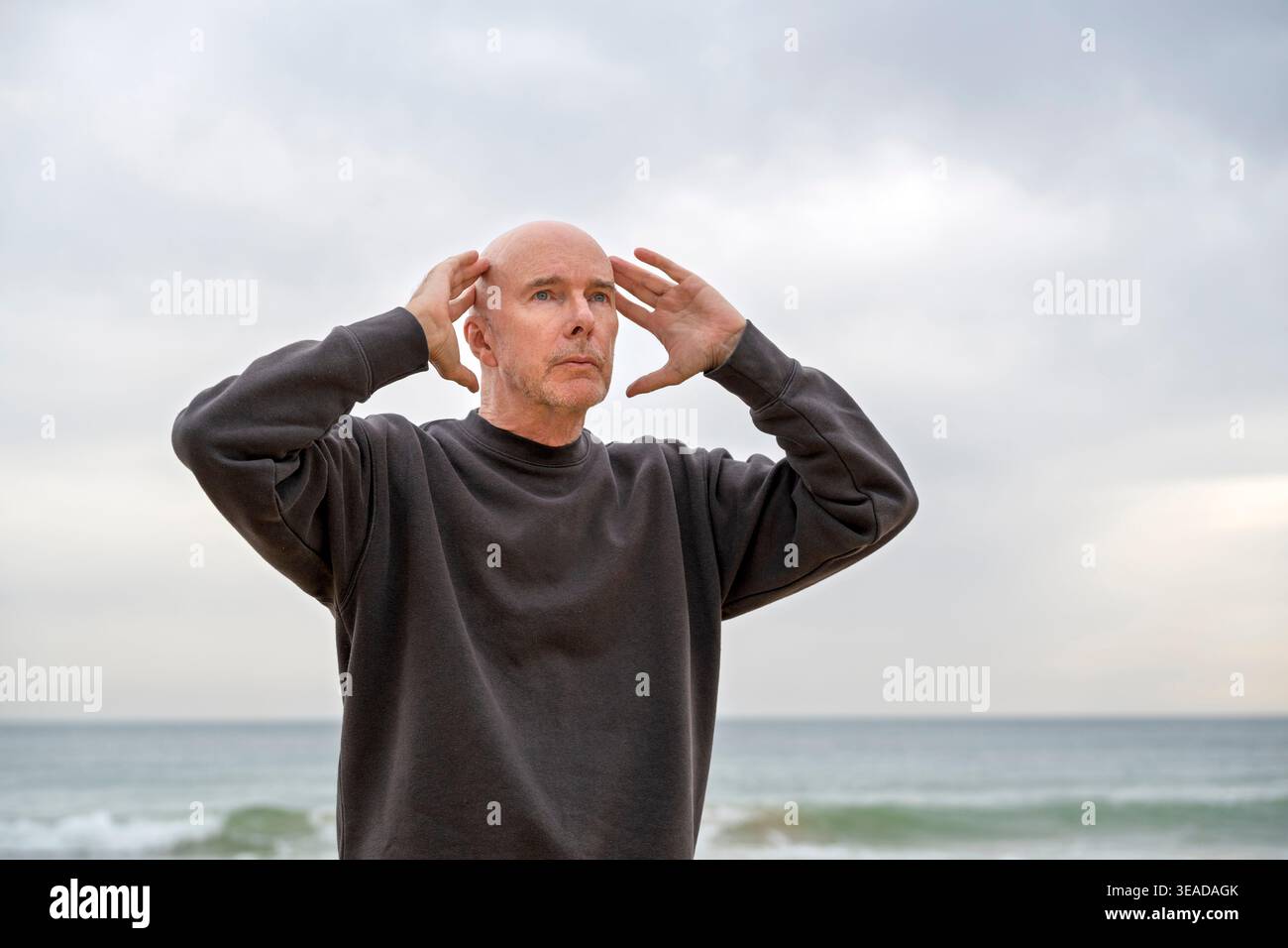 mature man standing with hands on head Stock Photo