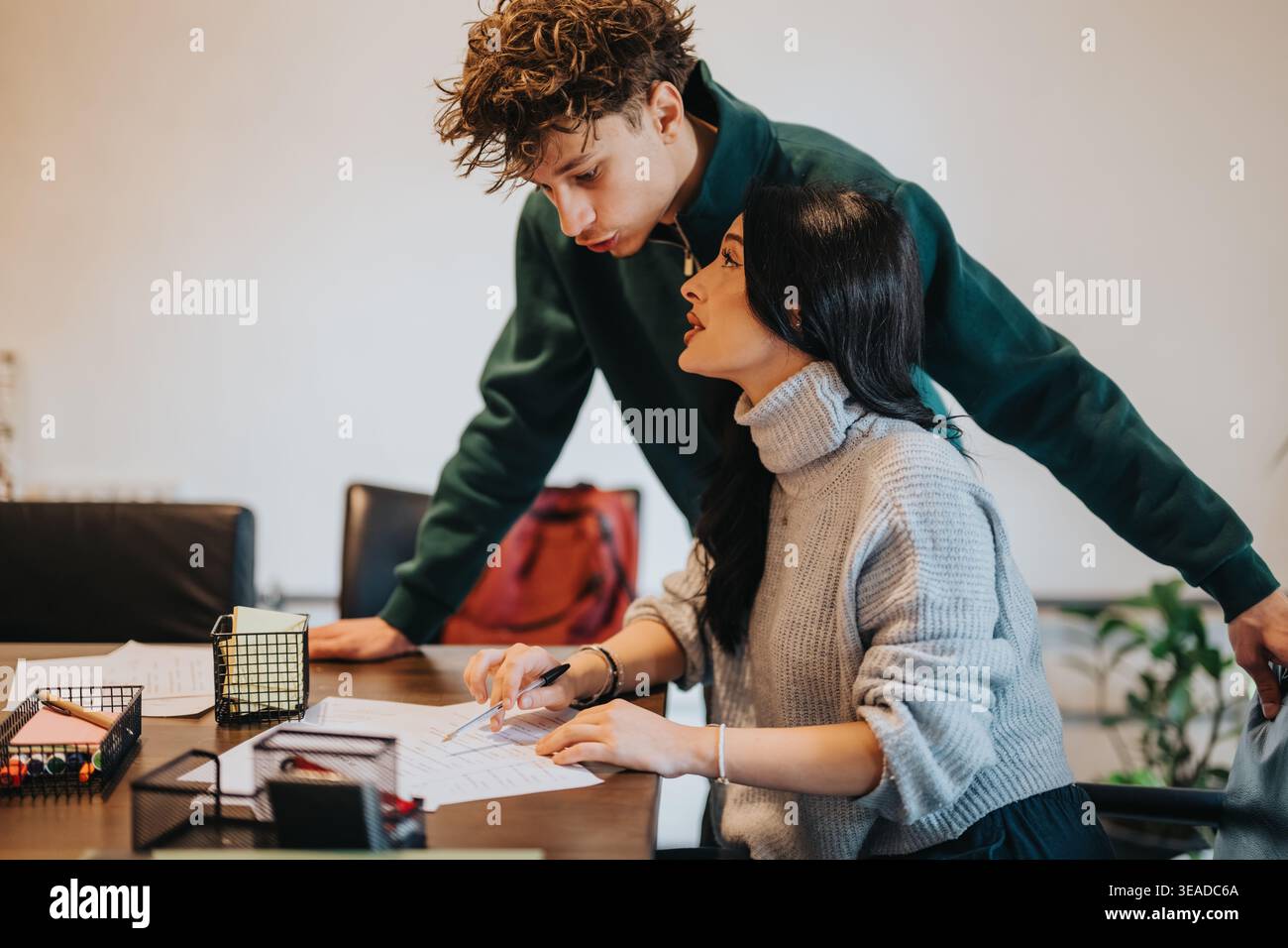 Two students studying together at a table collaborating on paperwork and homework Stock Photo