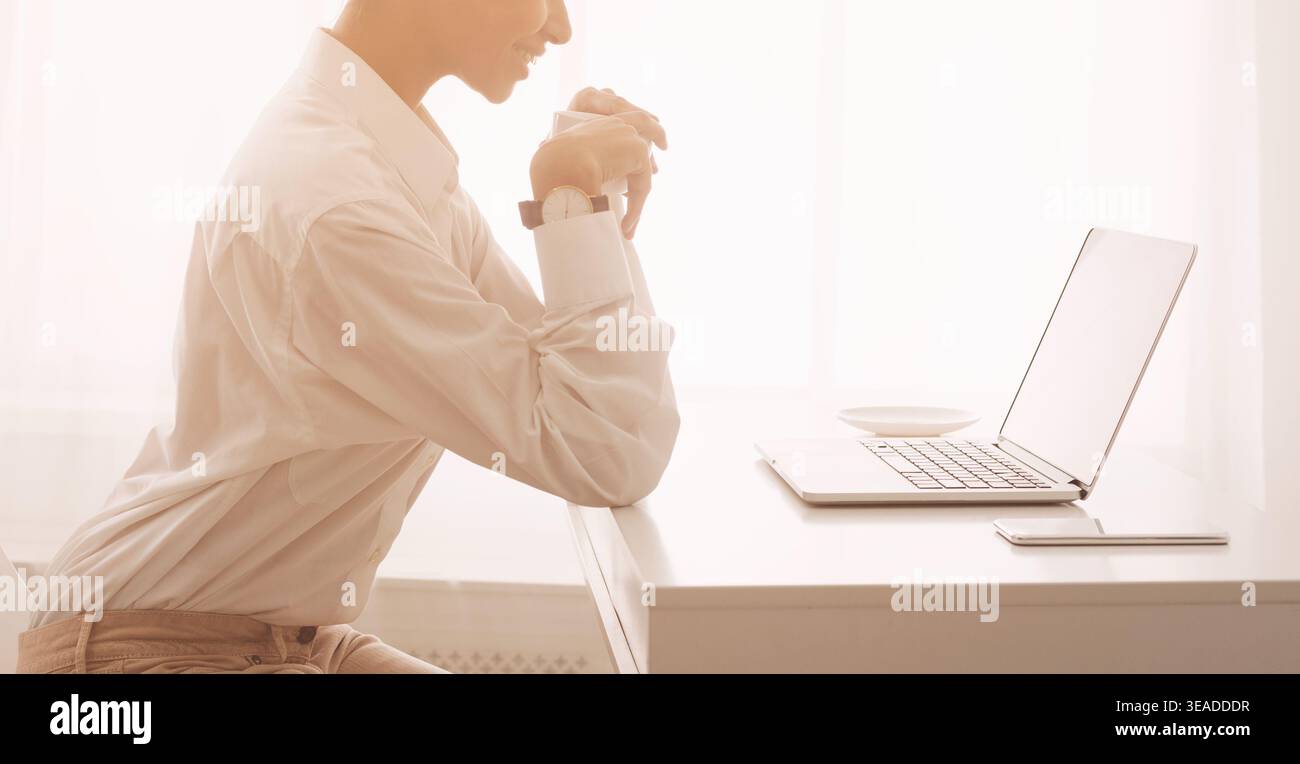 Freelancer working on laptop and drinking coffee Stock Photo
