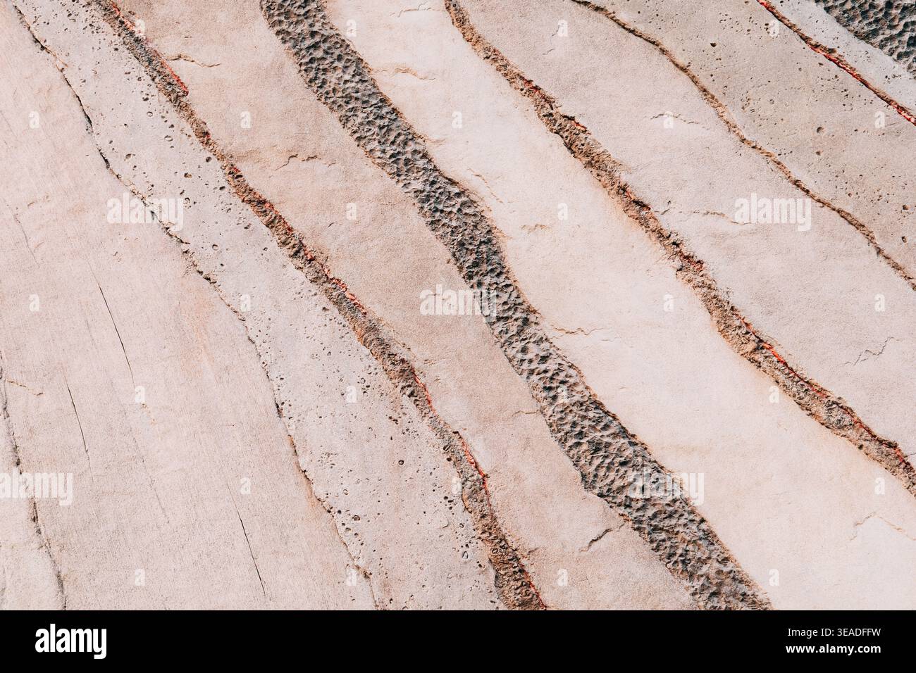 Abstract pattern showing diagonal lines with textured rock and rough sand, creating a dynamic surface background Stock Photo