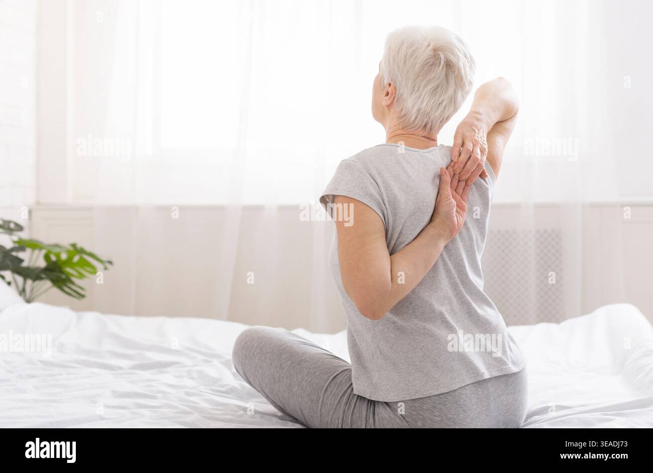 Elderly woman touching her hands behind her back Stock Photo