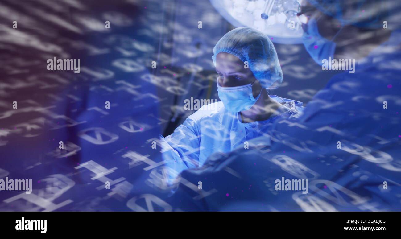 Operating lead surgeon gowned masked gloved bouffant capped in OR under lamp with data overlay Stock Photo