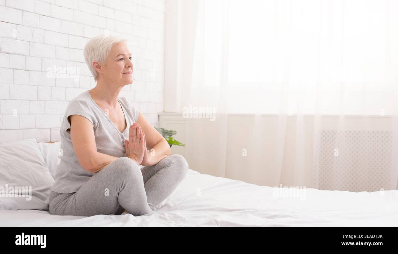 Young caucasian woman practicing yoga in bed Stock Photo