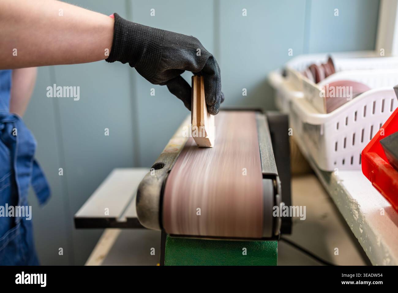 Woman’s Hands Guiding Wood Through Sanding Machine in Workshop Stock Photo