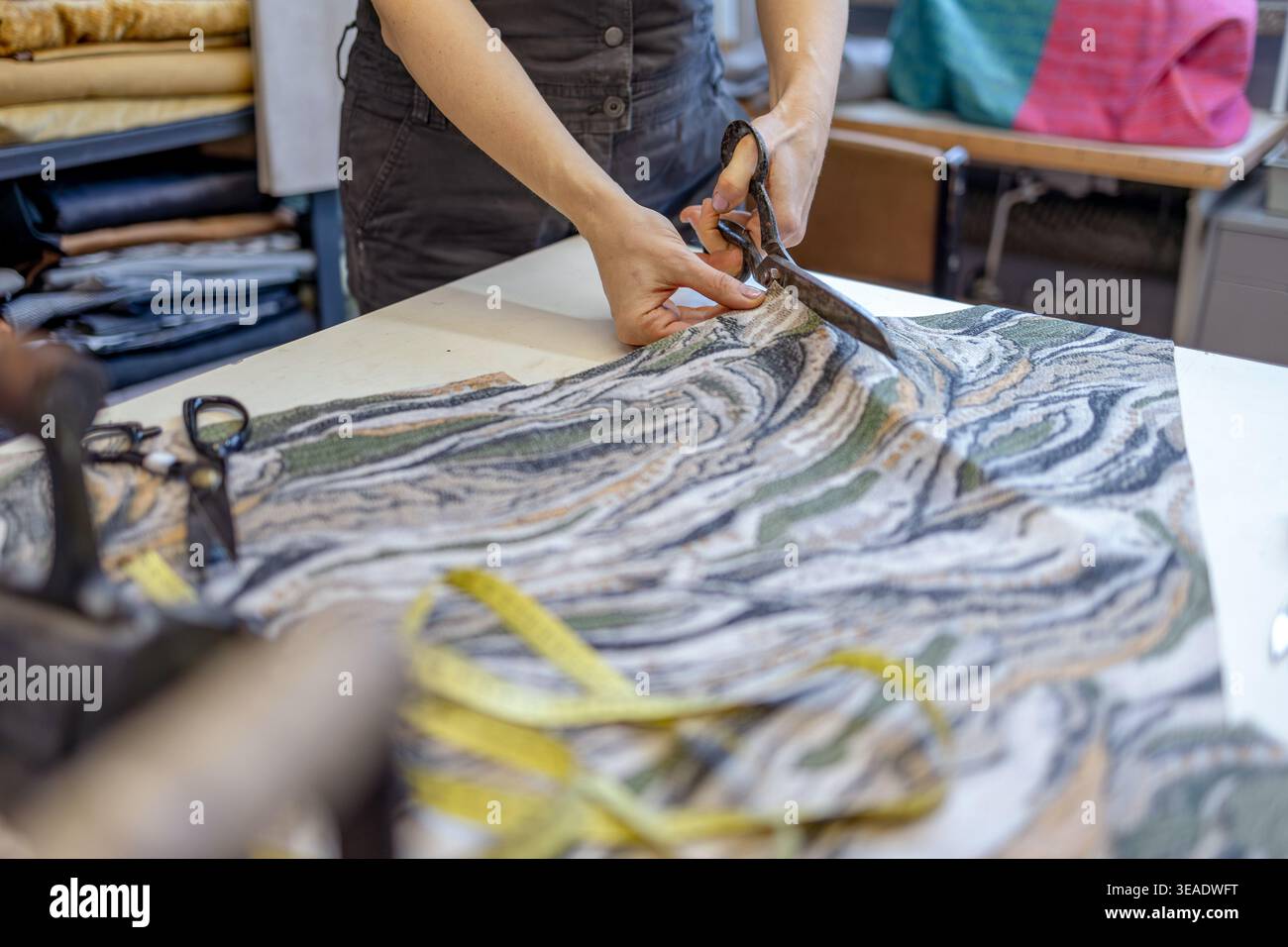 Cutting Fabric with Scissors on Worktable in Atelier Stock Photo