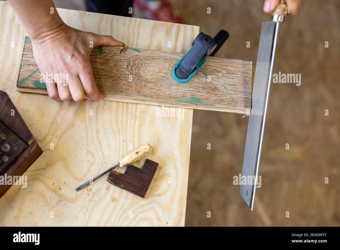Cutting Wood with Hand Saw on Workbench Stock Photo