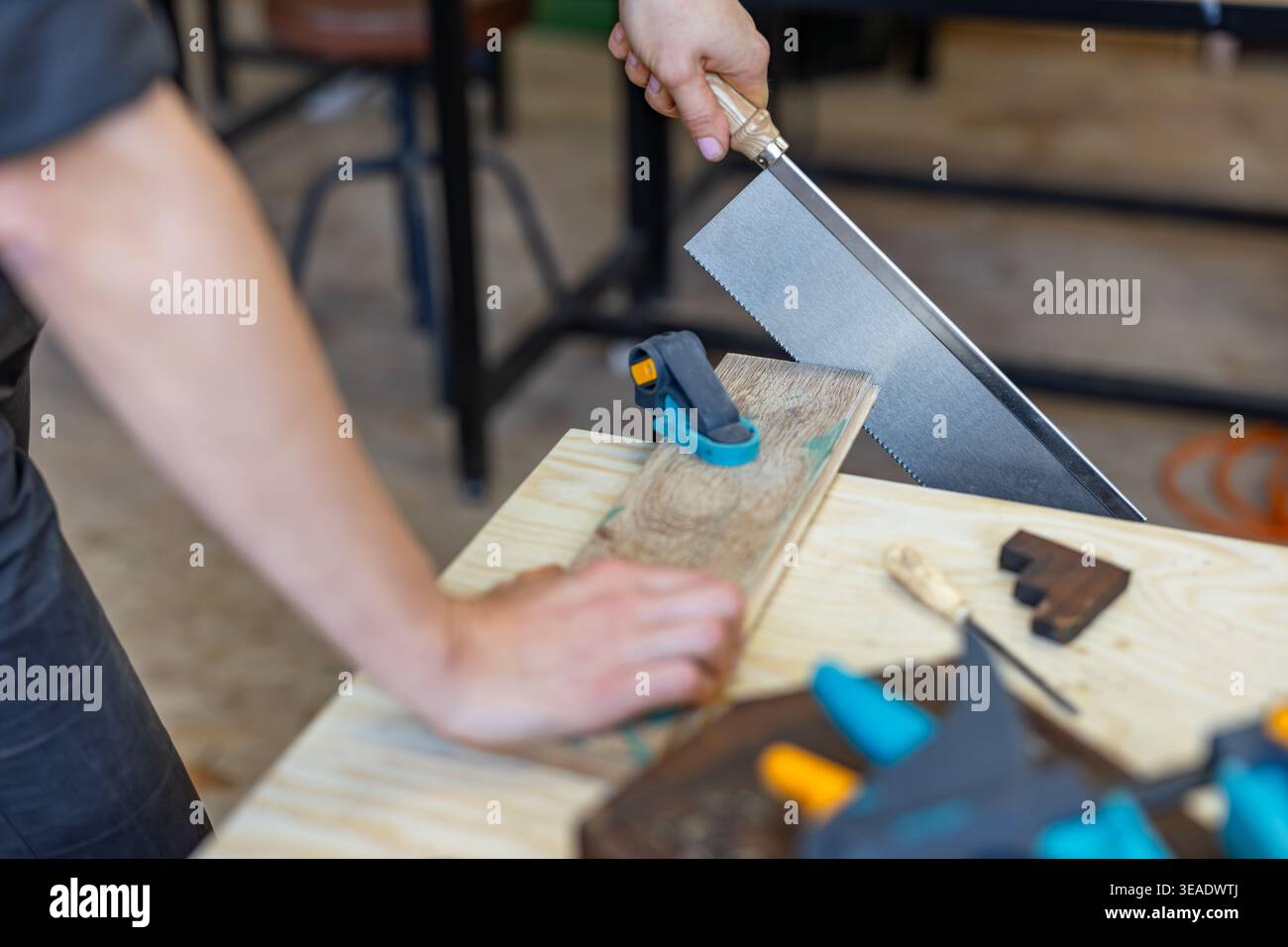 Cutting Wood with Hand Saw on Workbench Stock Photo
