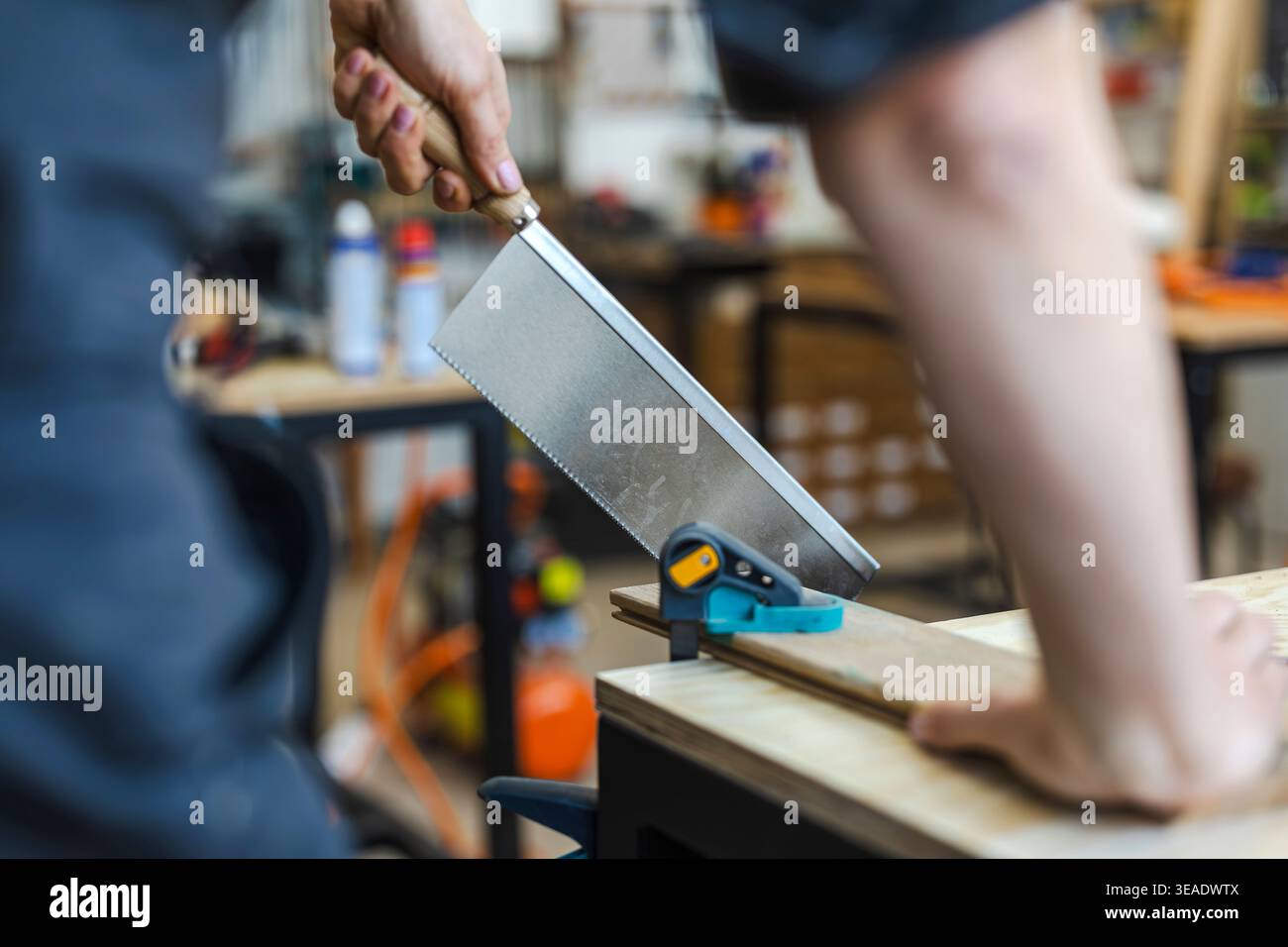 Cutting Wood with Hand Saw on Workbench Stock Photo