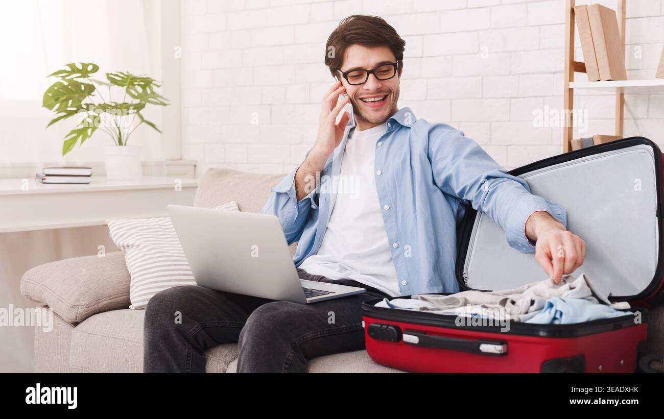 Man talking on phone and packing clothes Stock Photo