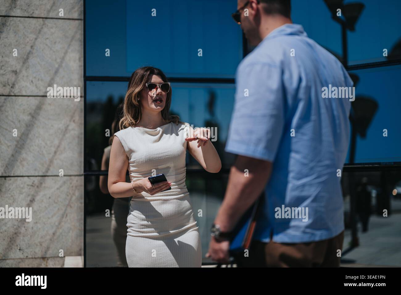 Business meeting between two professionals conversing outside a modern glass office building Stock Photo
