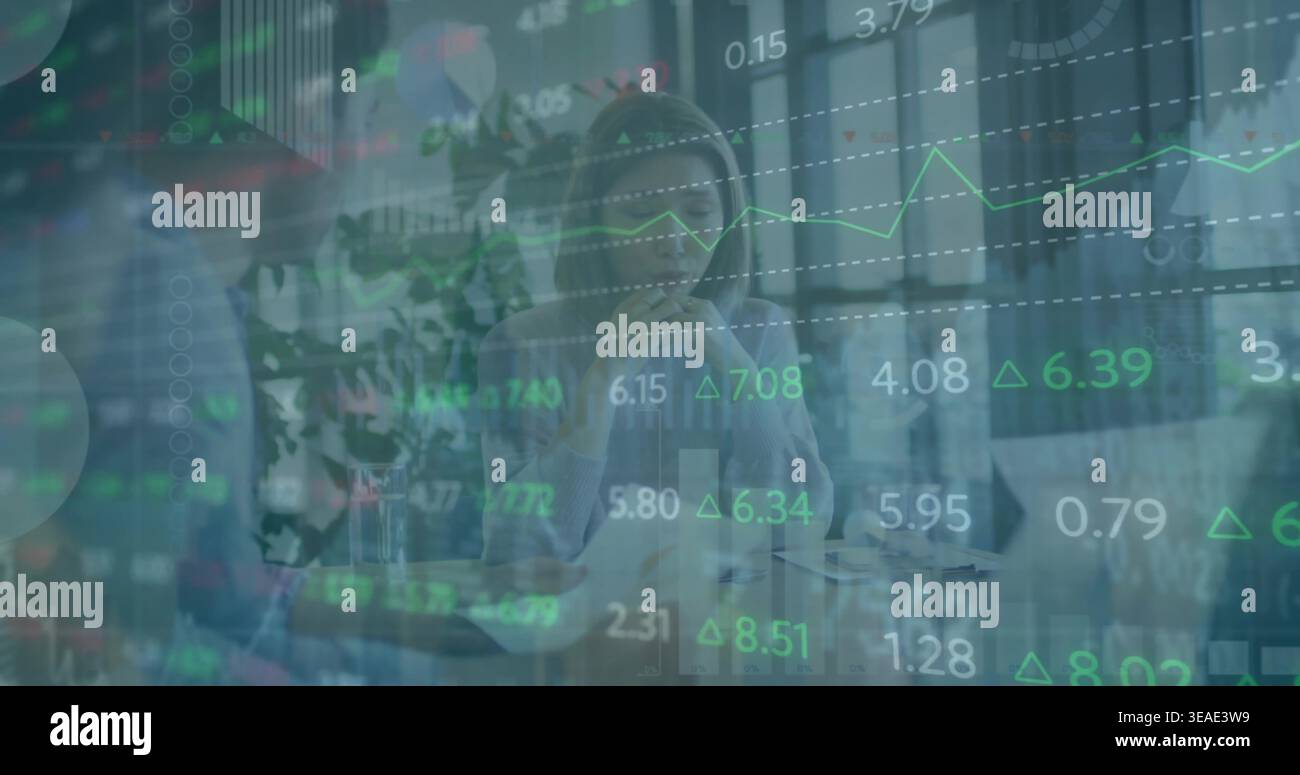 Thinking Asian woman wearing light blouse and listening in office, with laptop market charts Stock Photo