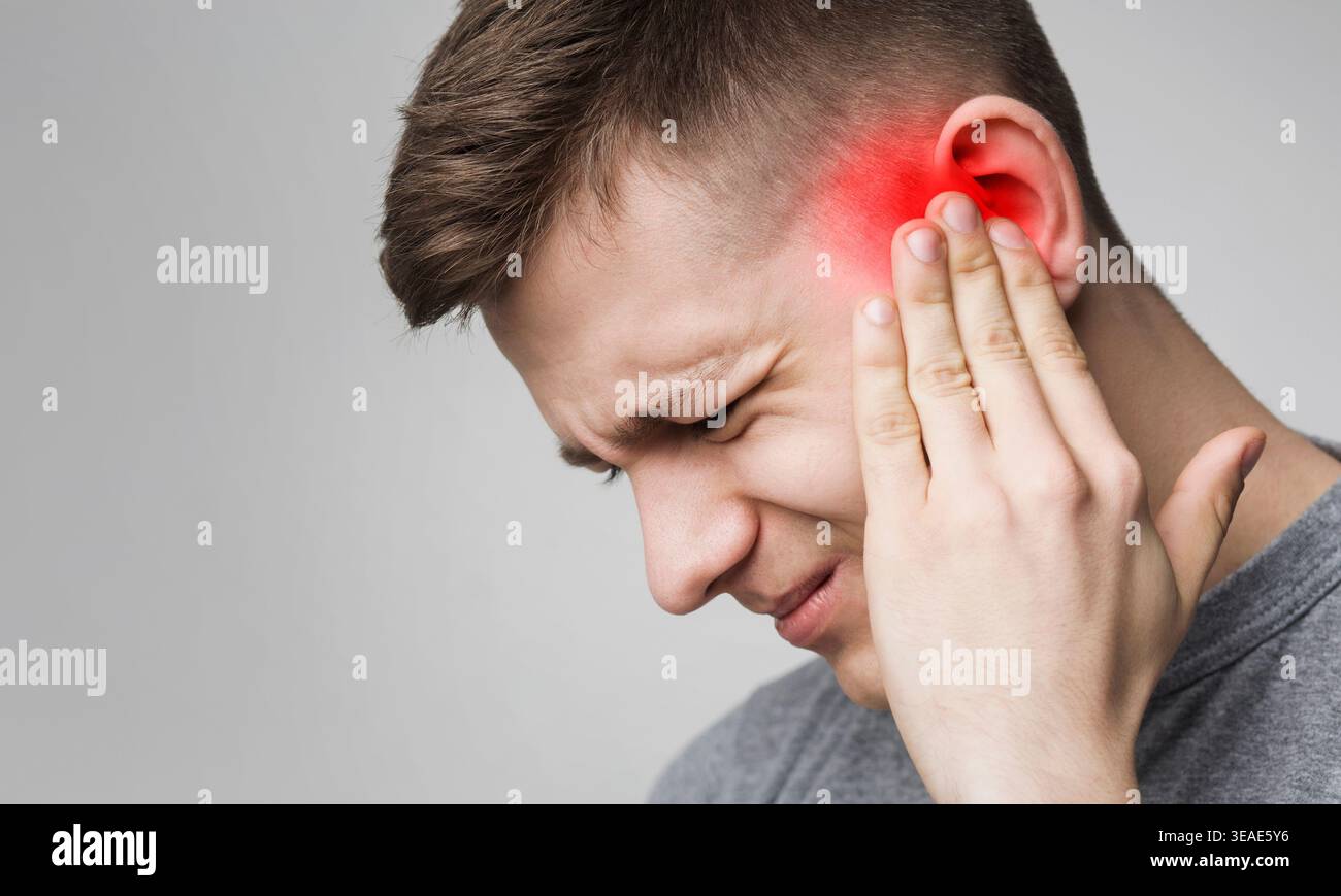 Young man has sore ear, suffering from otitis Stock Photo