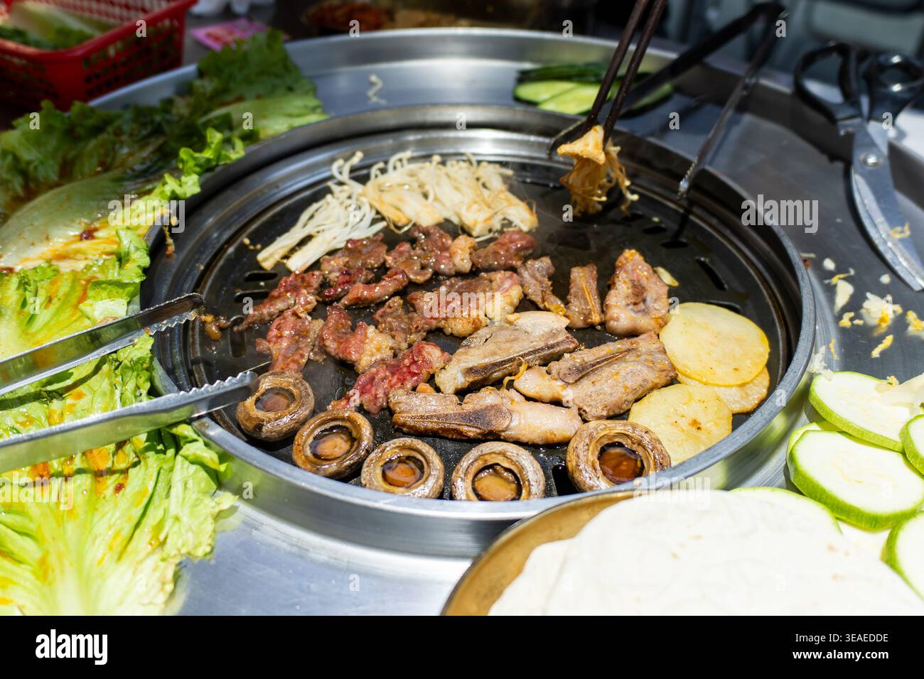 Korean BBQ Grill with Sizzling Meat, Mushrooms, and Vegetables on Hot Plate Stock Photo