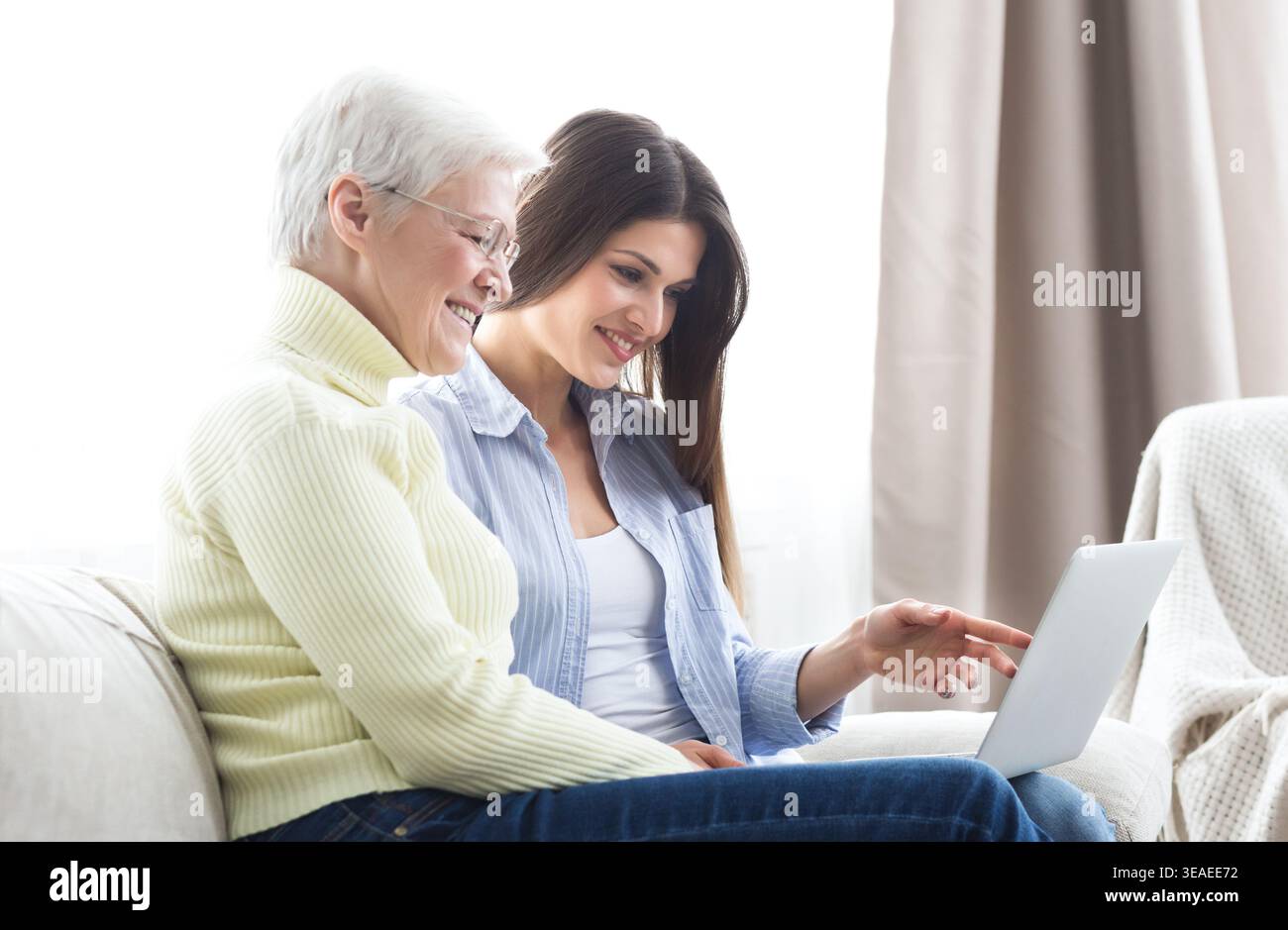 Daughter teaching her elderly mother using laptop Stock Photo