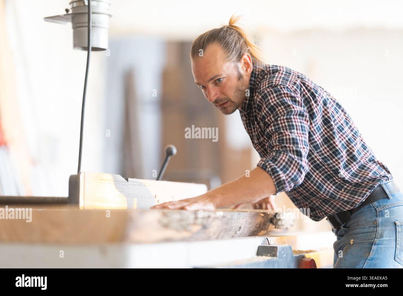 Woodworker carefully operating woodworking machine in workshop Stock Photo