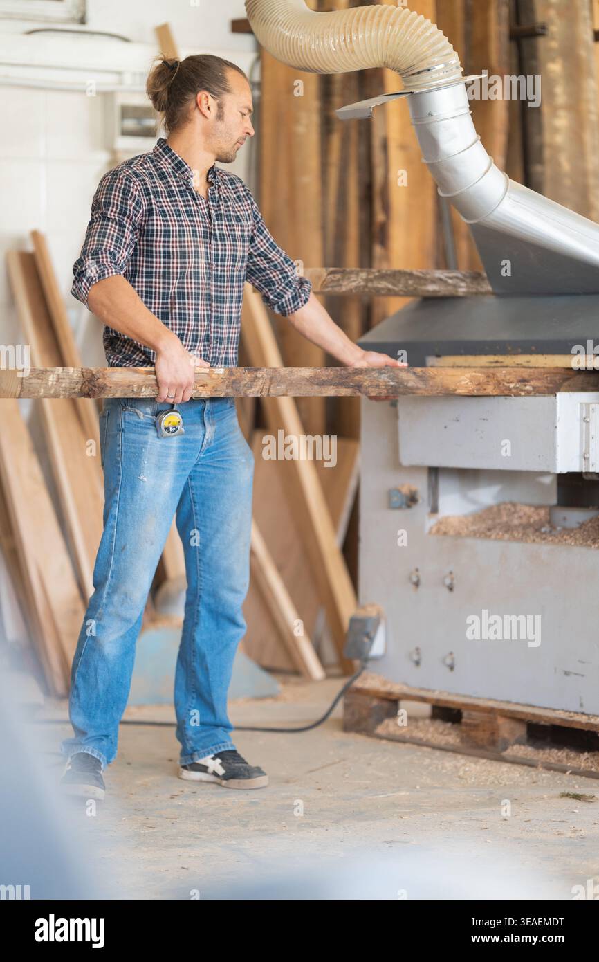 Carpenter working with wood plank using planer machine Stock Photo