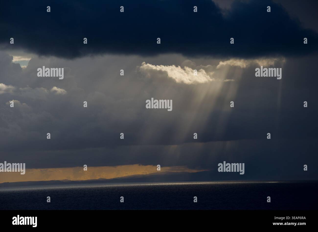 Sunbeams Breaking Through Dark Storm Clouds Over Ocean Stock Photo