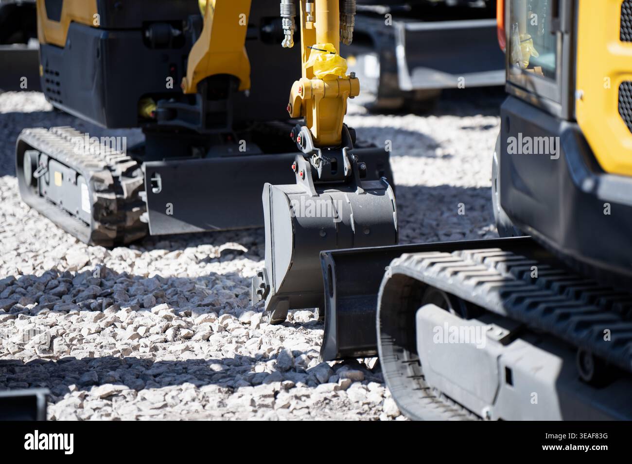 Multiple compact excavators on gravel with trench buckets, blades and ...