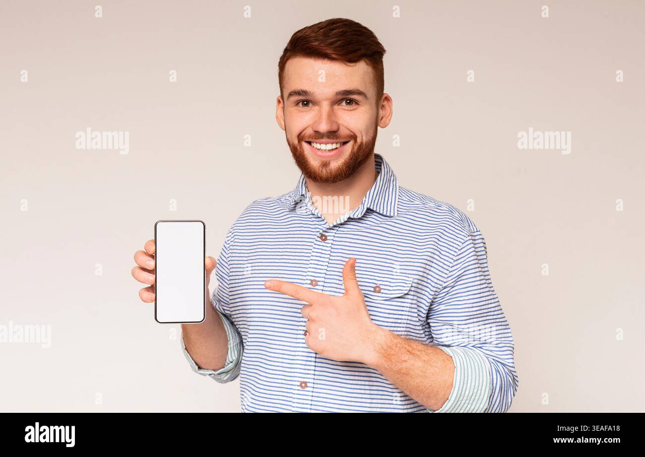 Smiling millennial man holding latest slim cellphone Stock Photo