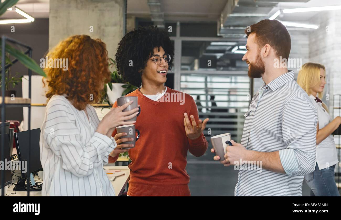 Young diverse colleagues sharing ideas during coffee break Stock Photo