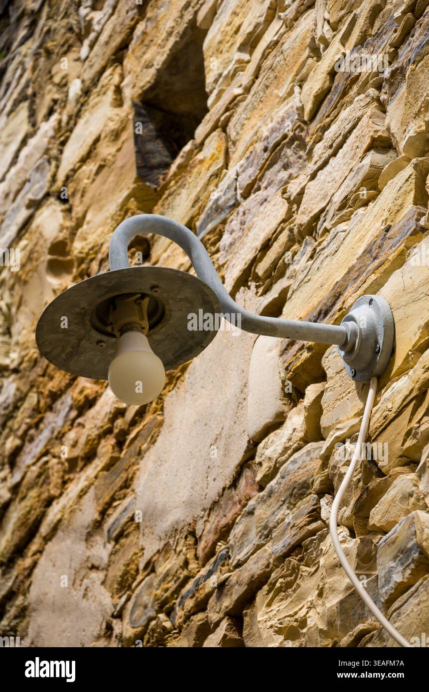 Rustic Wall Lamp on Weathered Stone Exterior Stock Photo