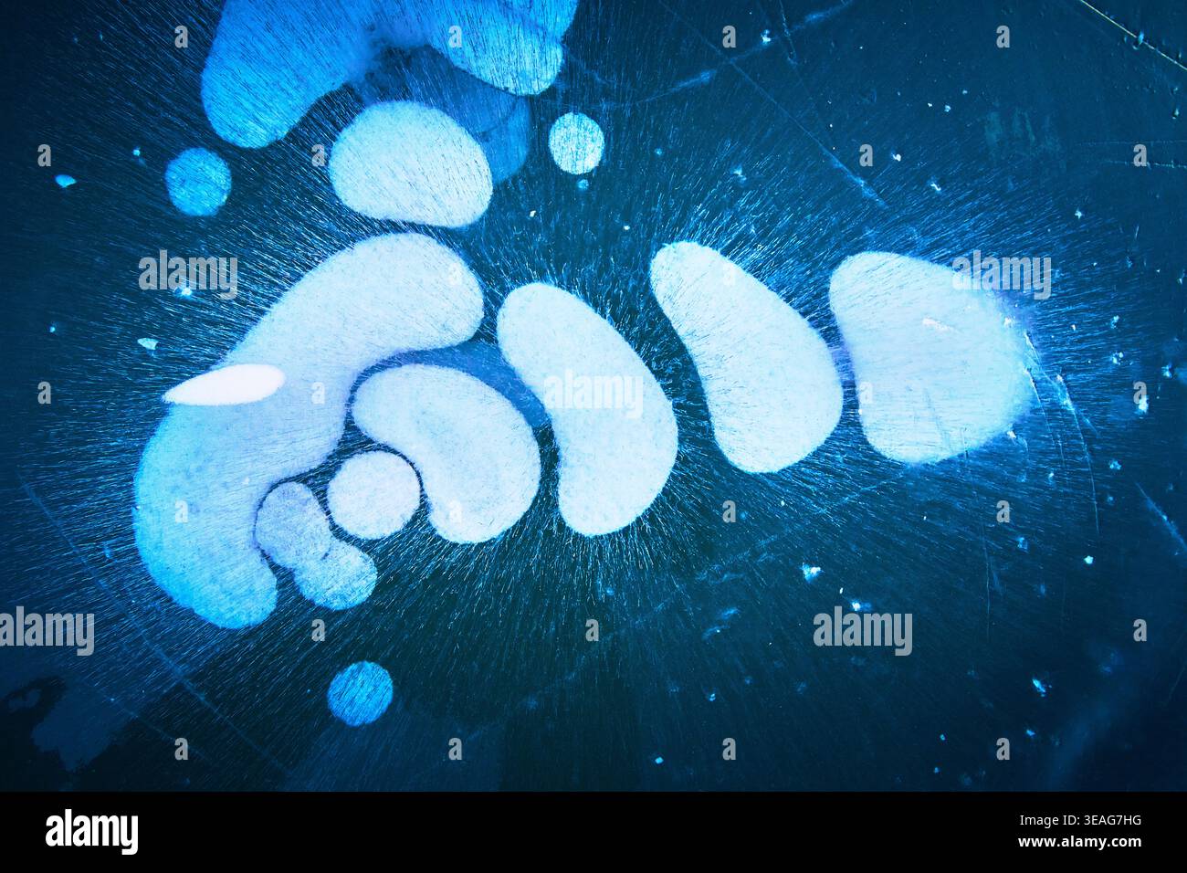 Frozen Methane Bubbles Under Ice on Winter Lake Surface with Blue Abstract Patterns Stock Photo