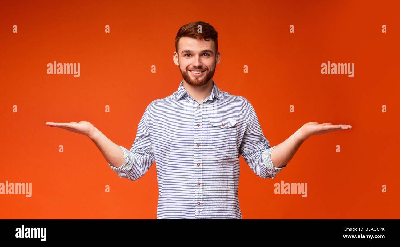 Young Man Smiling and Posing With Outstretched Arms in Front of an Orange Background Stock Photo