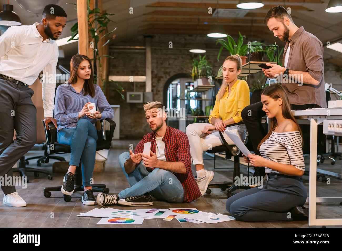Team Collaboration in Modern Office Discussing Project Details on Printed Graphs and Charts Stock Photo