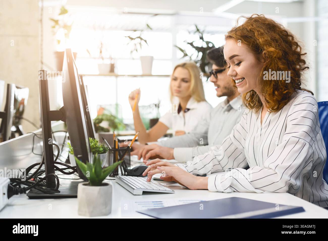 Collaborative Workspace With Professionals Using Computers and Engaging in Teamwork During the Day Stock Photo