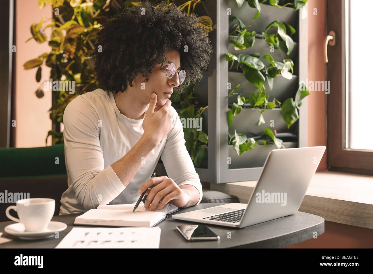 Confident young man working on laptop sitting in cafe Stock Photo