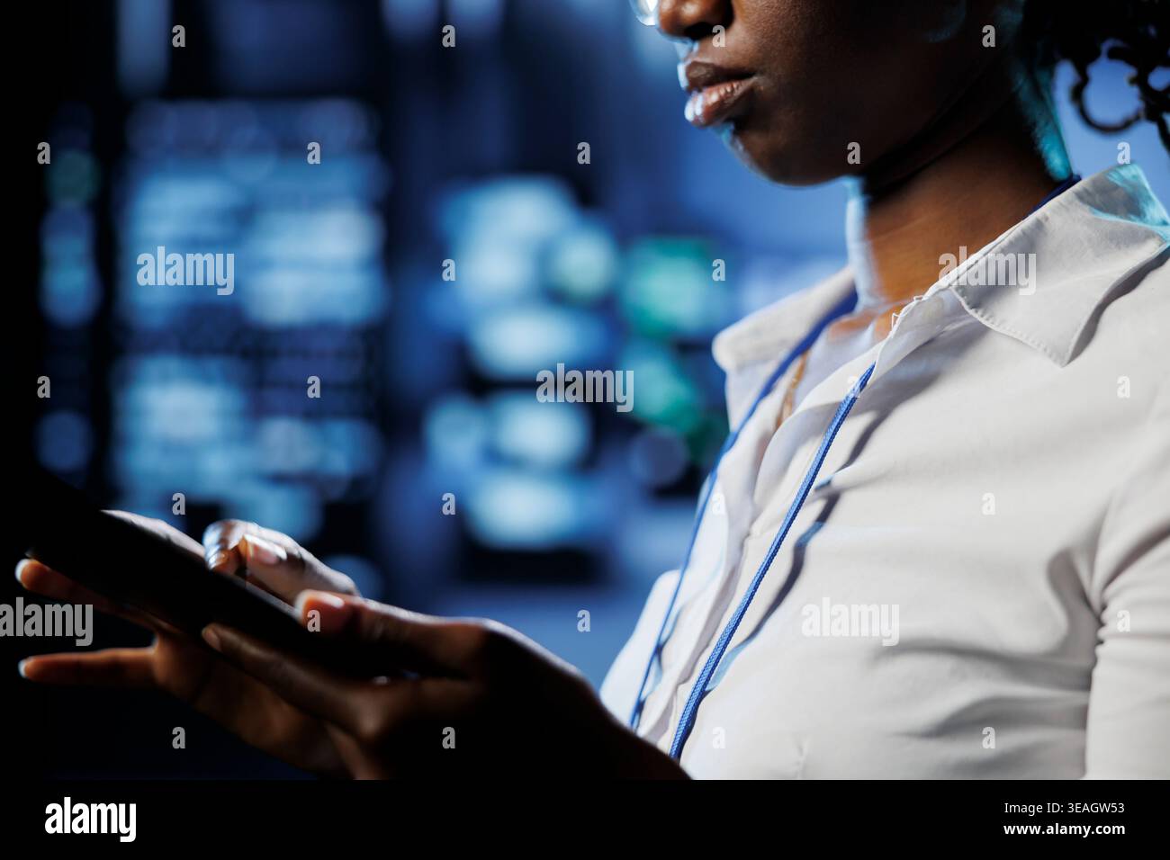 Focused admin in data center uses tablet to prevent server machines overload. Expert between server mainframes using device to ensure enough network bandwidth for smooth operations Stock Photo