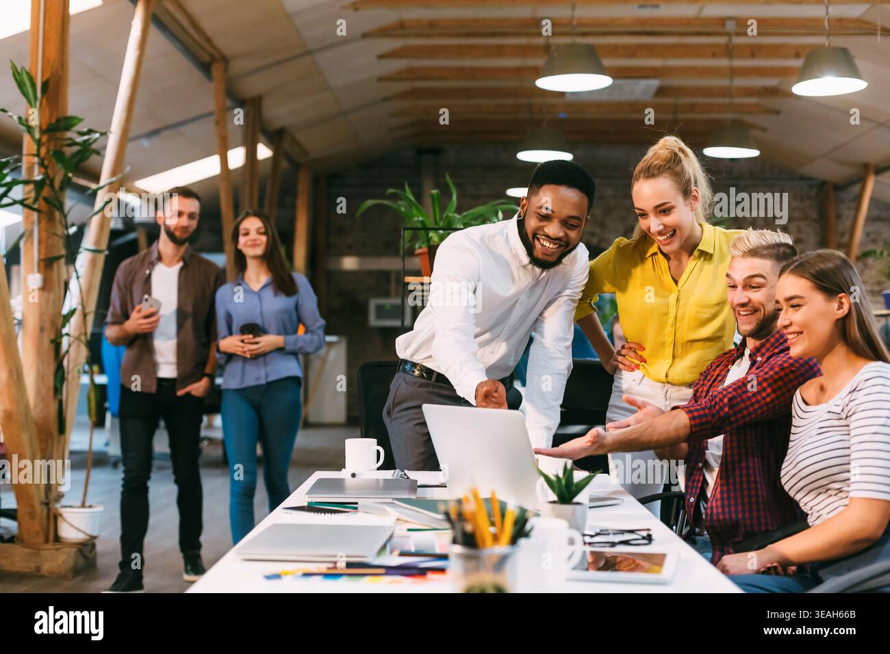 Young colleagues working on laptop and discussing new project Stock Photo