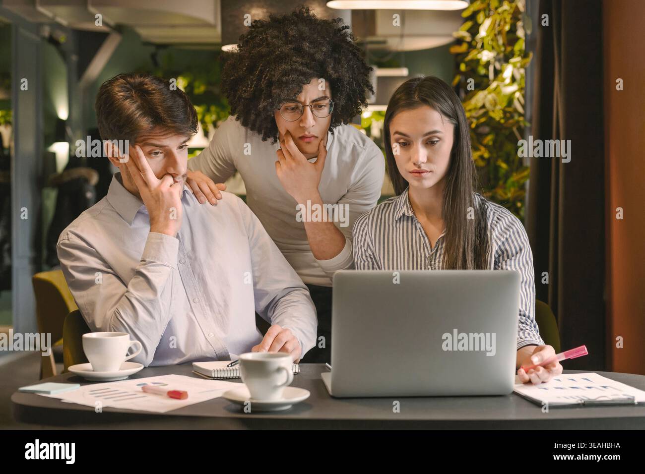 Three Colleagues Collaborating on a Project at a Modern Workspace Stock Photo