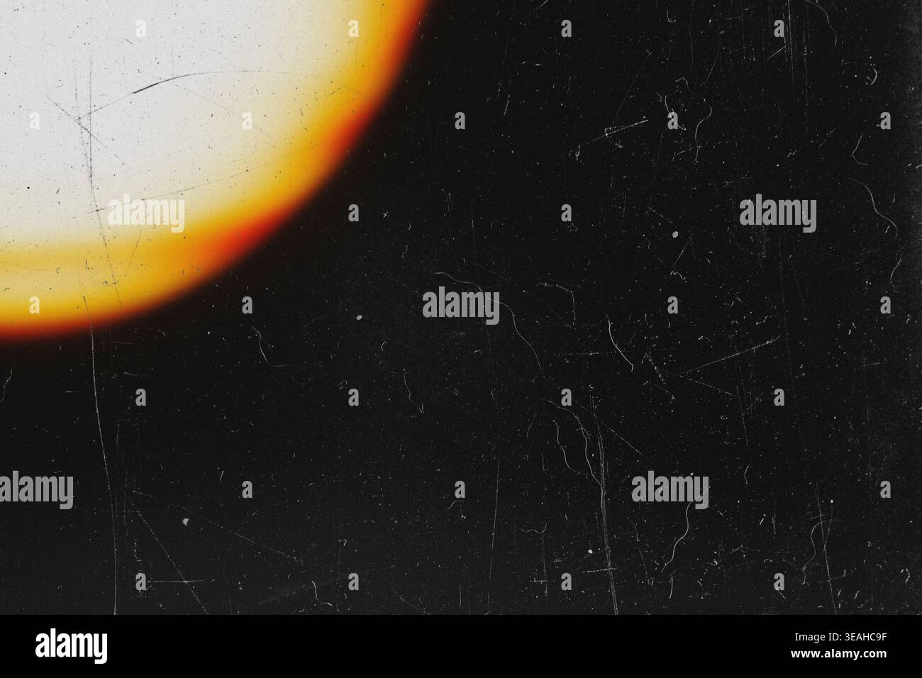 Bright yellow circular lens flare on dark retro film background with dust Stock Photo