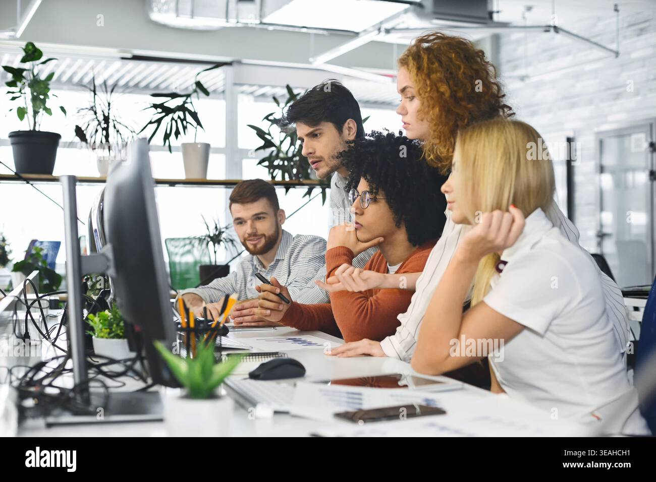 Young team analyzing new information, looking at computer Stock Photo