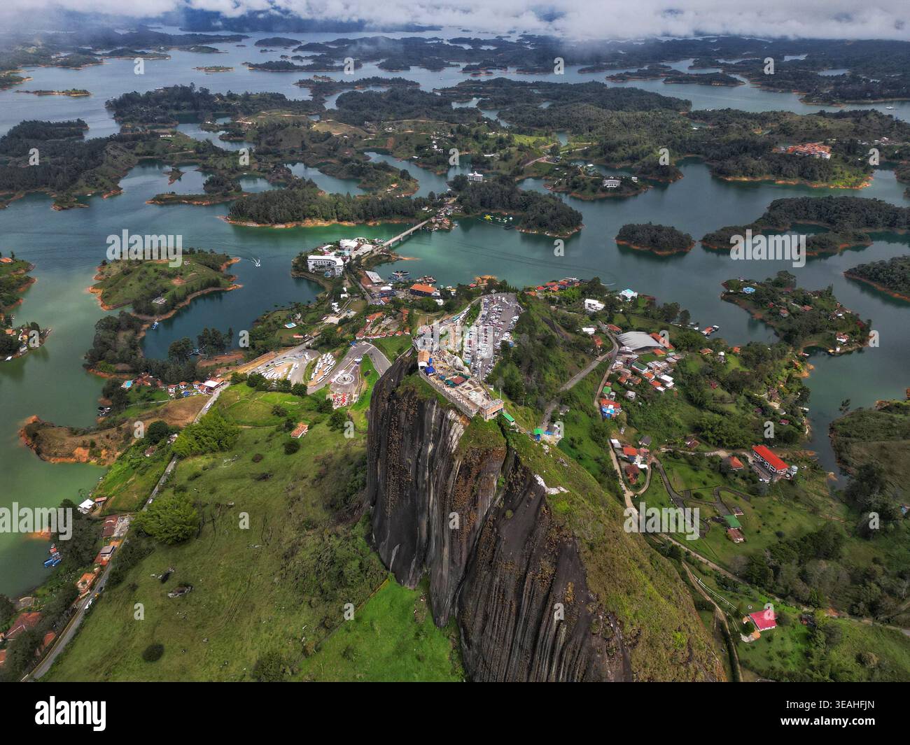 Aerial View Of El Penon De Guatape Monolith Rising Above The Turquoise 