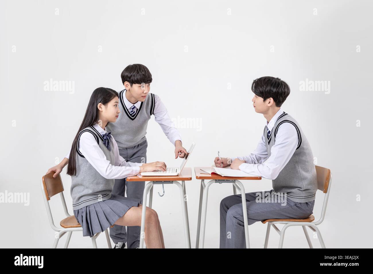 A group of students in school uniforms work together on a project in a ...