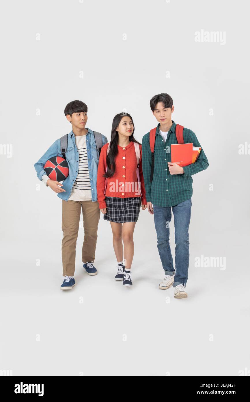 Three students from different cultural backgrounds walk together on a campus. Stock Photo