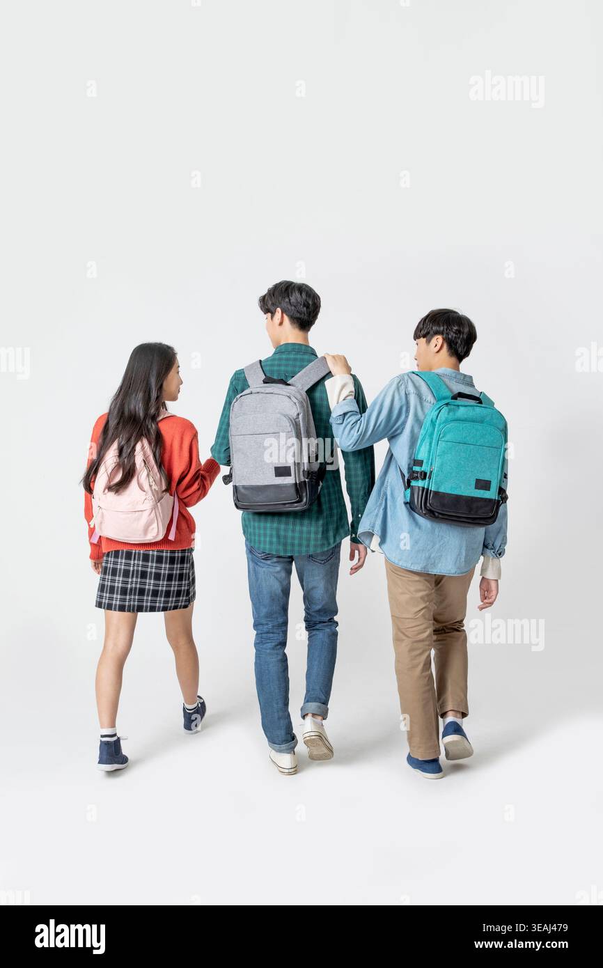 Three students walking together, each with a backpack, against a white background. Stock Photo
