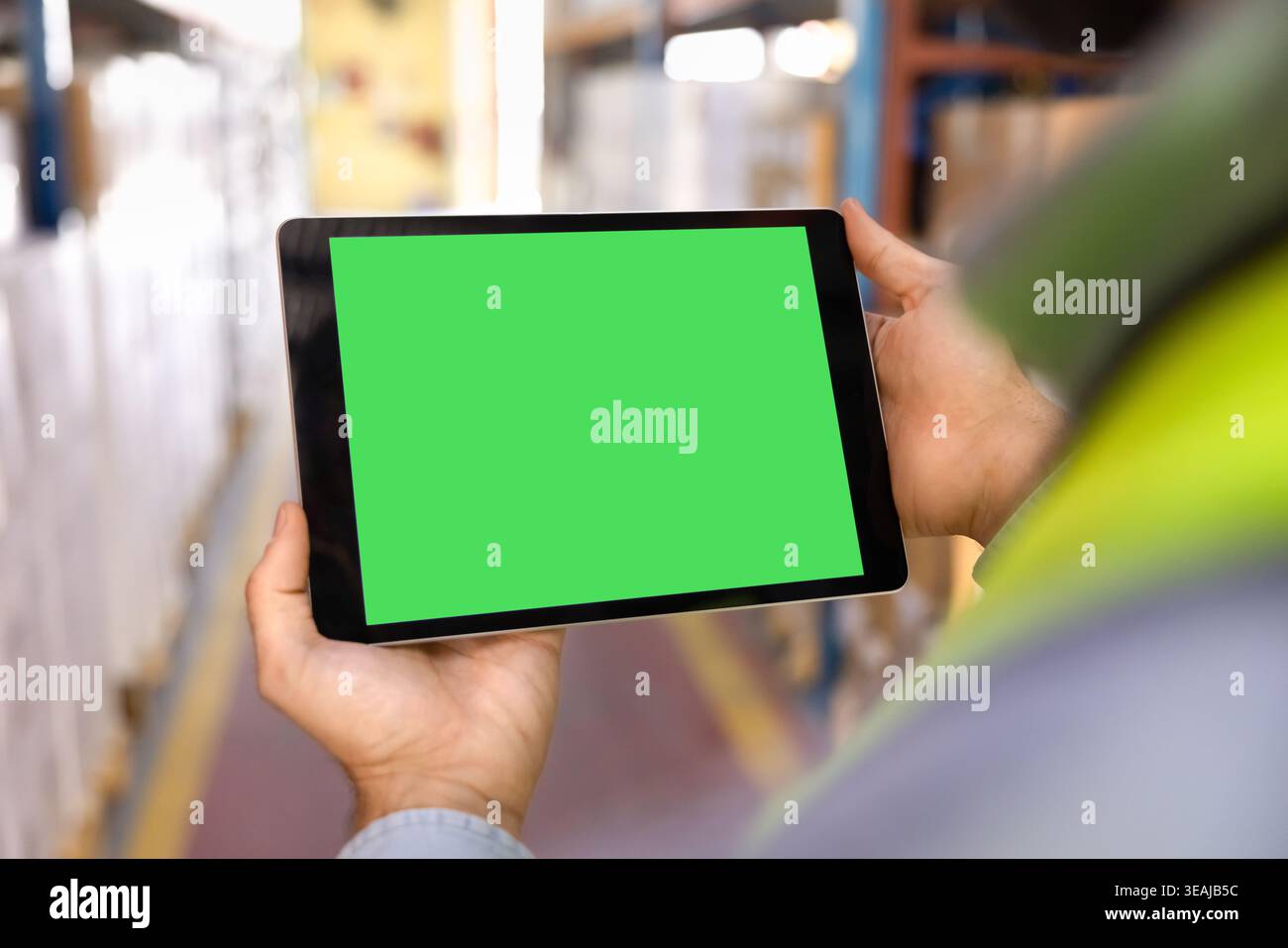 Male worker using digital tablet with green screen in warehouse Stock Photo