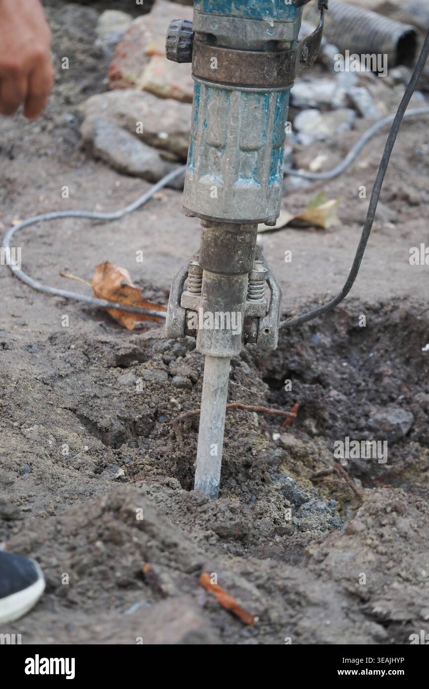 Worker uses tool to dig in ground for construction task Stock Photo