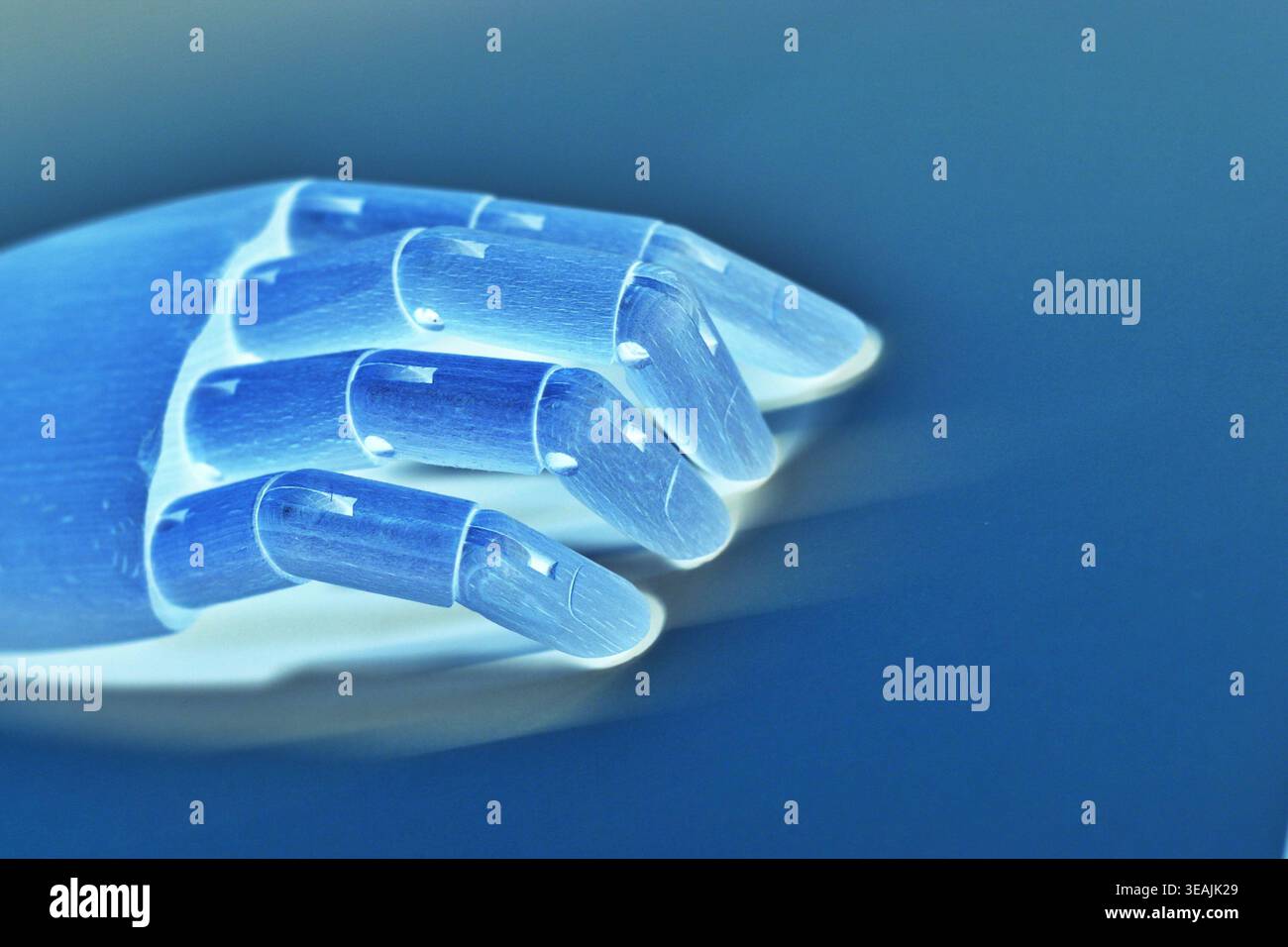 Close-up side view of a neon blue robotic hand isolated against a blue background in a monochromatic futuristic style. The image emphasizes artificial Stock Photo
